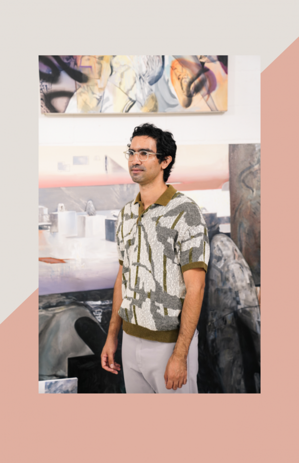 artist Leo Castenada standing in his studio wearing a gray an white patterned polo and gray pants.